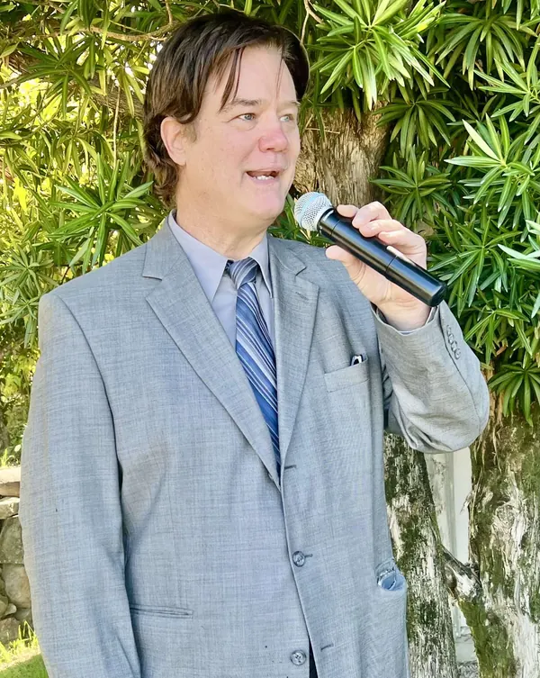 DJ Mike Flanagan speaking into a microphone at an outdoor event